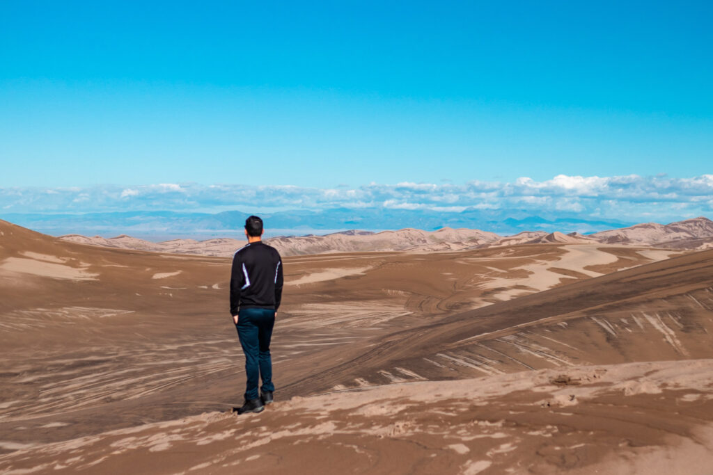 A picture of a man walking on the sand dunes